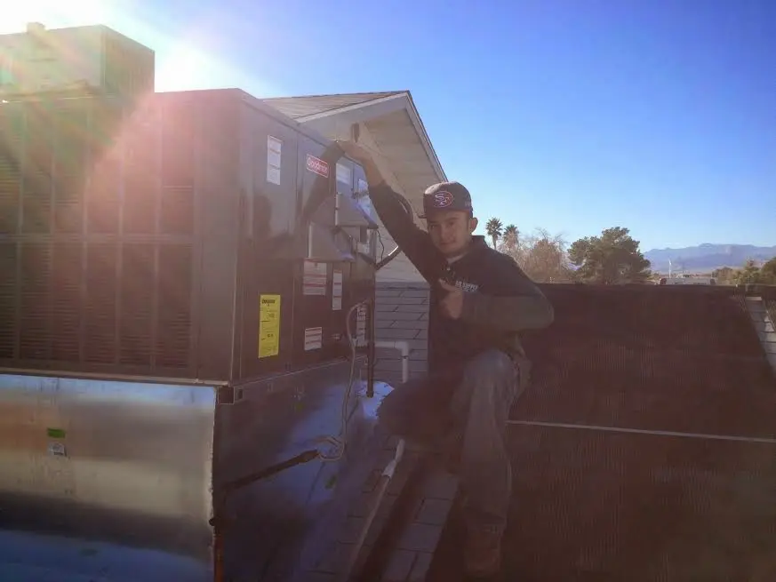 HVAC technician performing Air Duct Cleaning on a rooftop unit in Altadena